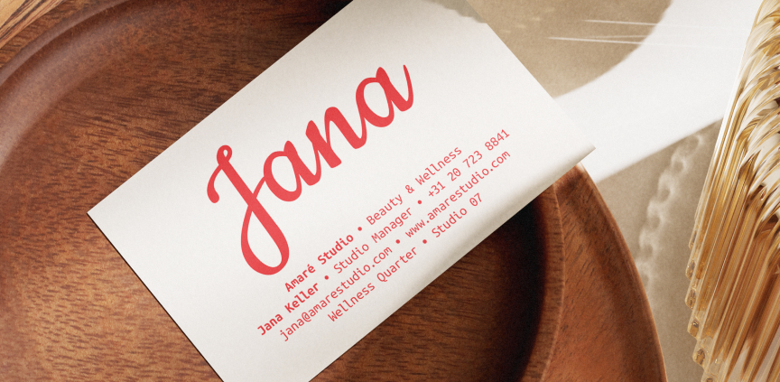 Business card with the name Jana and contact details placed on a wooden tray next to a decoration made of natural materials.
