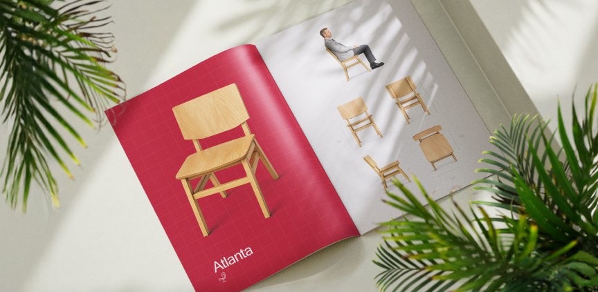 An open brochure with photos of a wooden chair on red and white pages, surrounded by green plants.